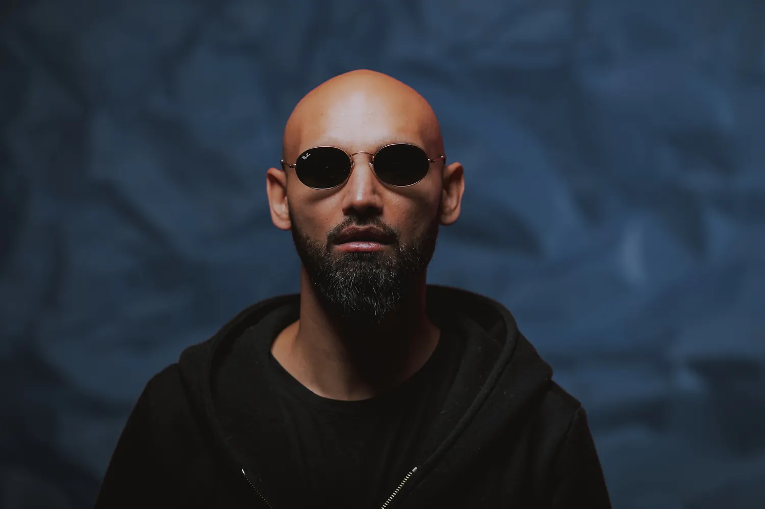 Bultech in a black hoodie against a blue backdrop