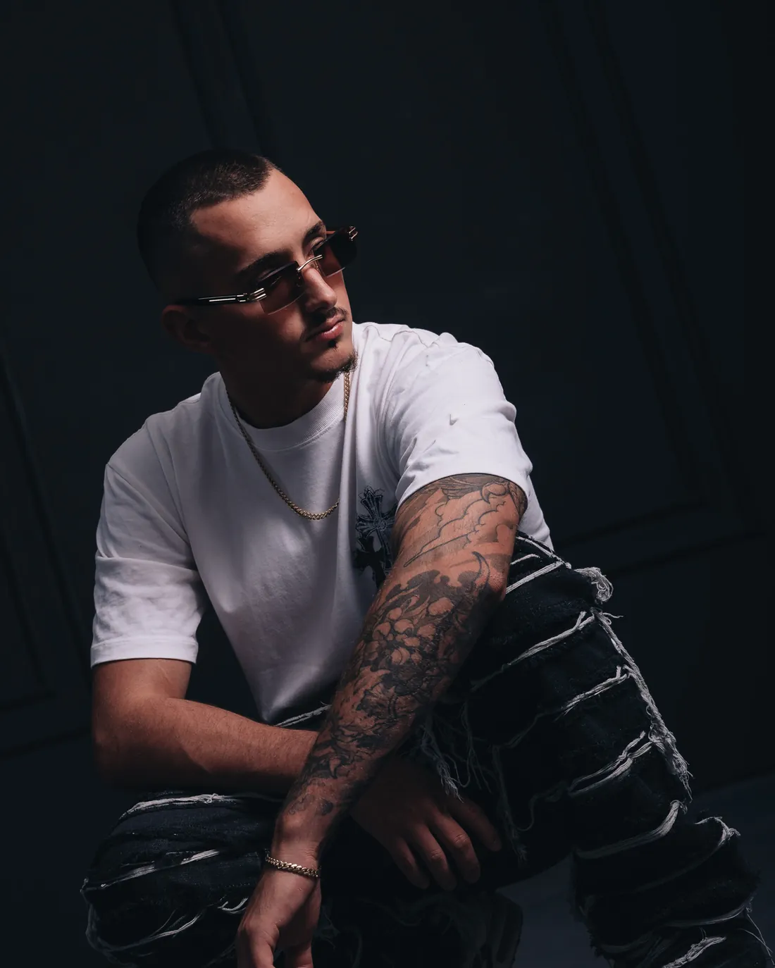 Mindslash crouching in a white T-shirt in a dark studio