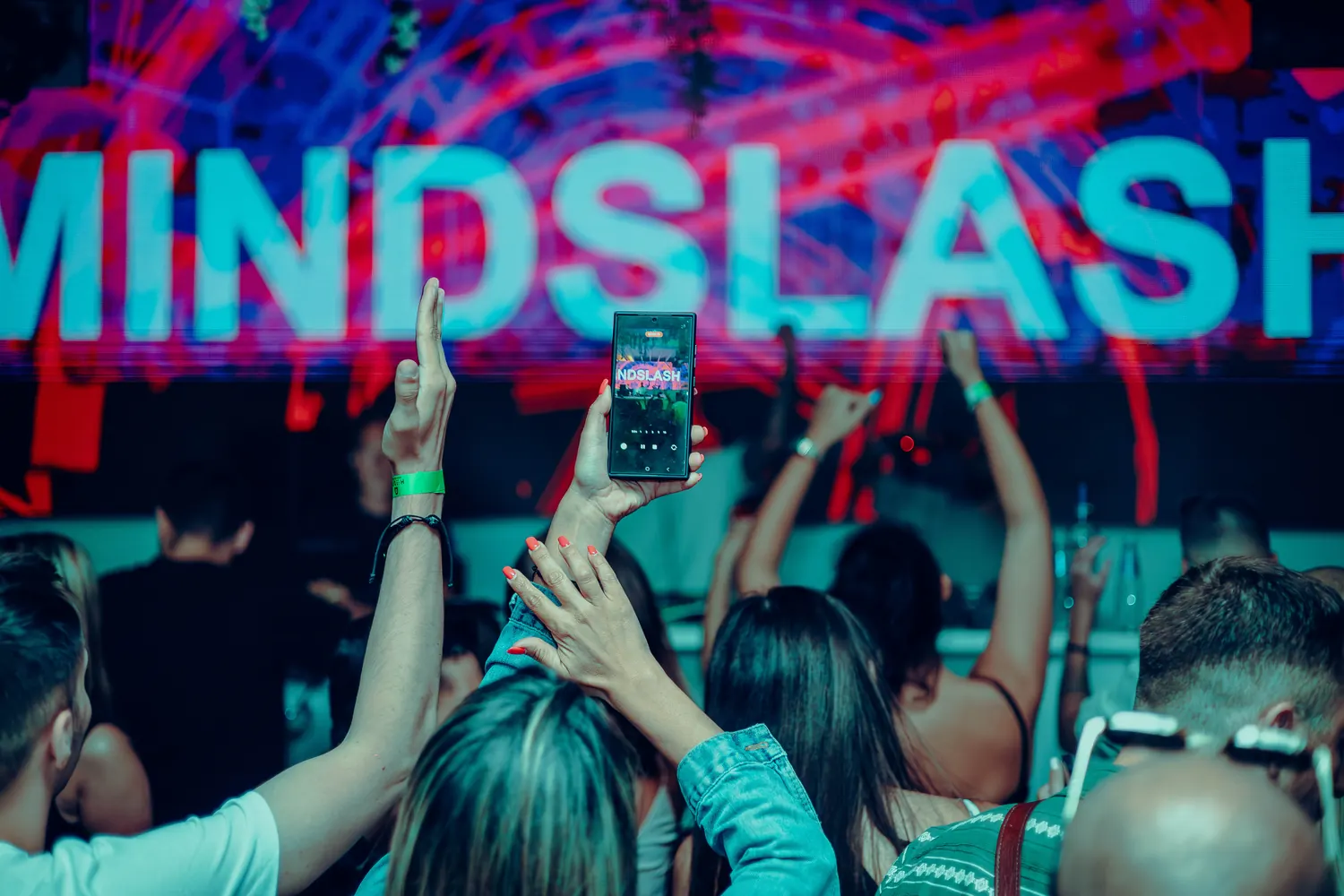 Mindslash raising his hand to the crowd under a MINDSLASH sign