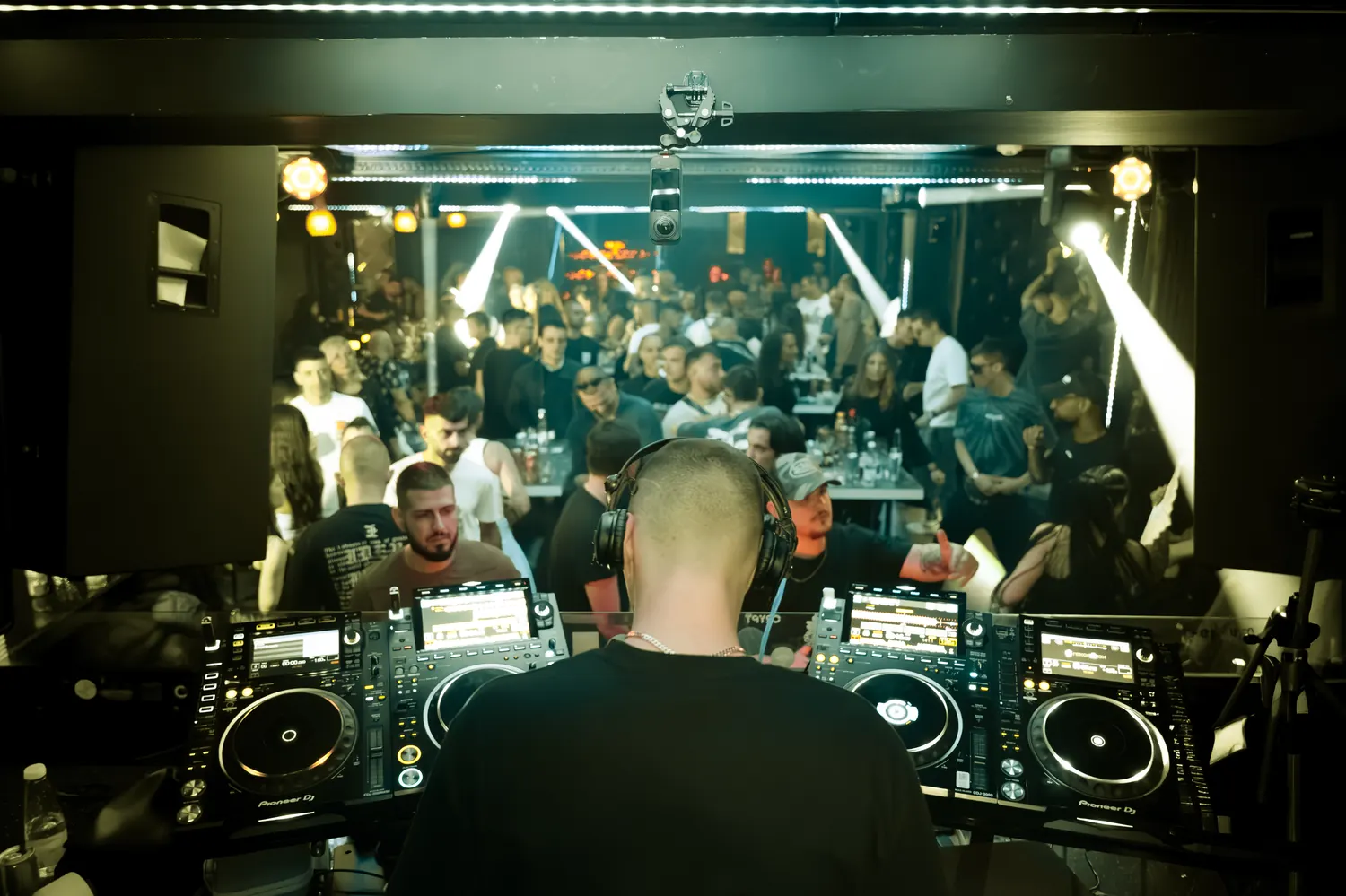 A packed club seen from behind the decks