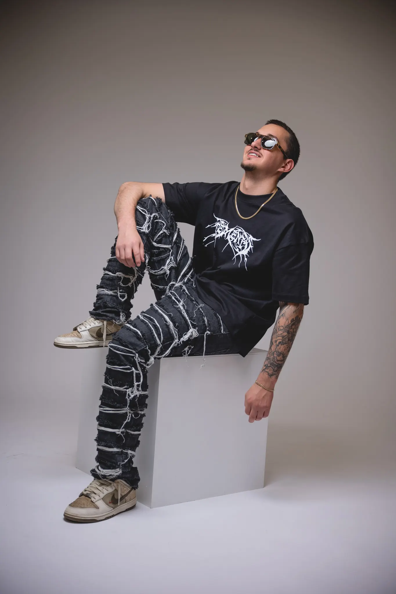 Mindslash seated on a white cube in a studio