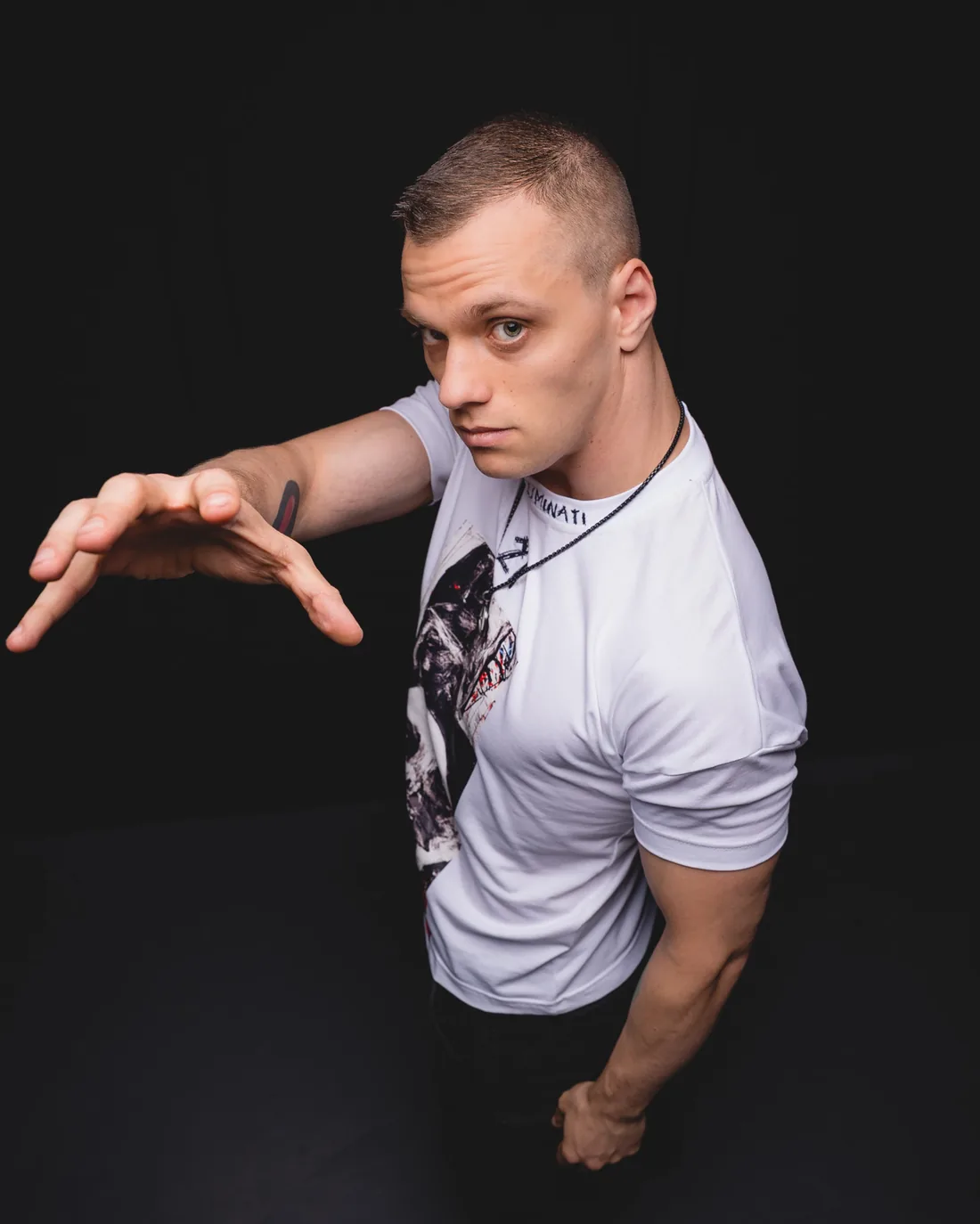 Shadowmaw reaching towards the camera in a white T-shirt